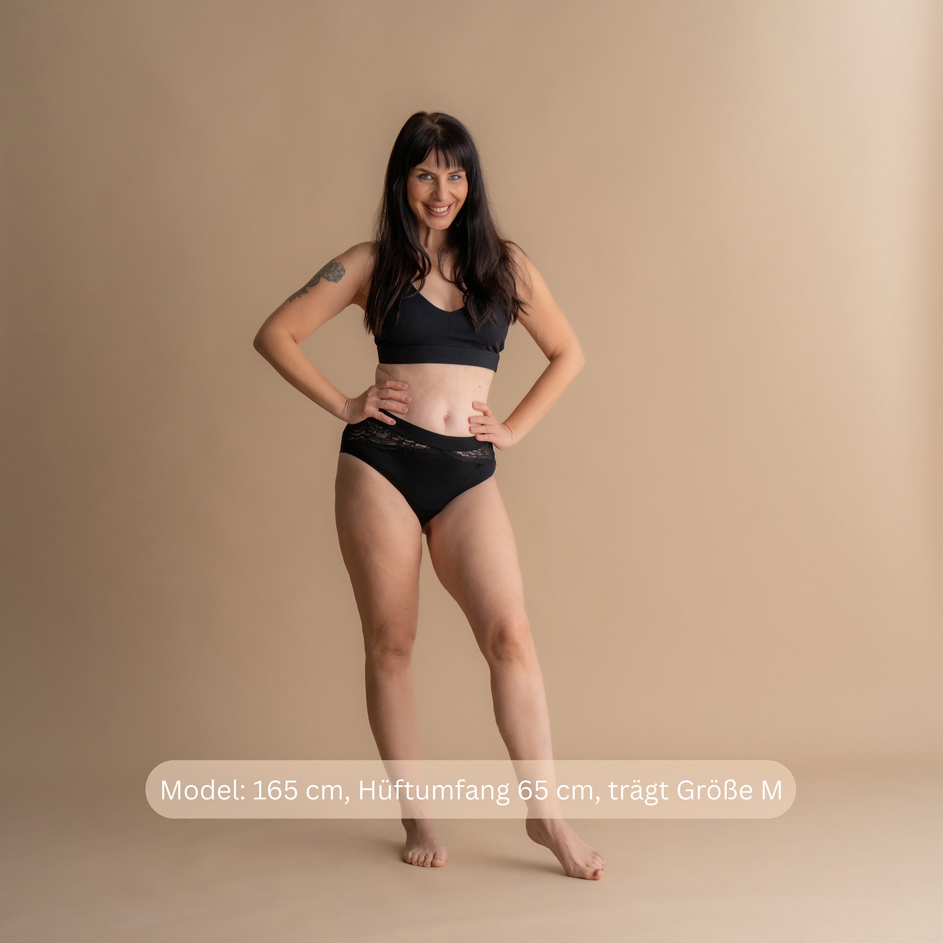 Ganzkörper-Frontansicht eines Models in der schwarzen Floena Leakproof Bamboo Lace Brief, Spitzen-Periodenunterwäsche aus Bambus, mit Spitzenbund