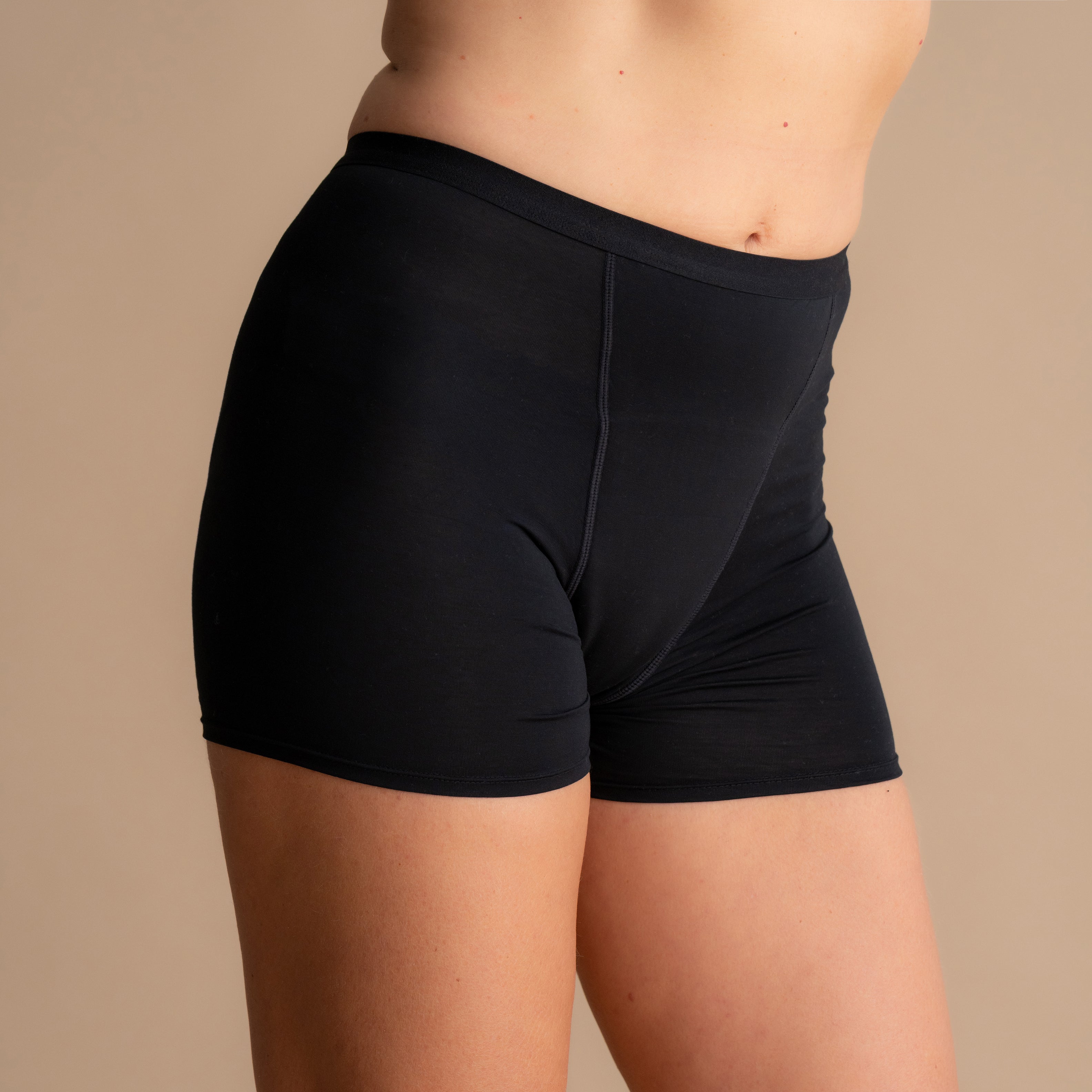 Vorderansicht der schwarzen Floena Leakproof Bamboo Sleep Short Perioden-Schlafshorts am Model vor beigem Hintergrund