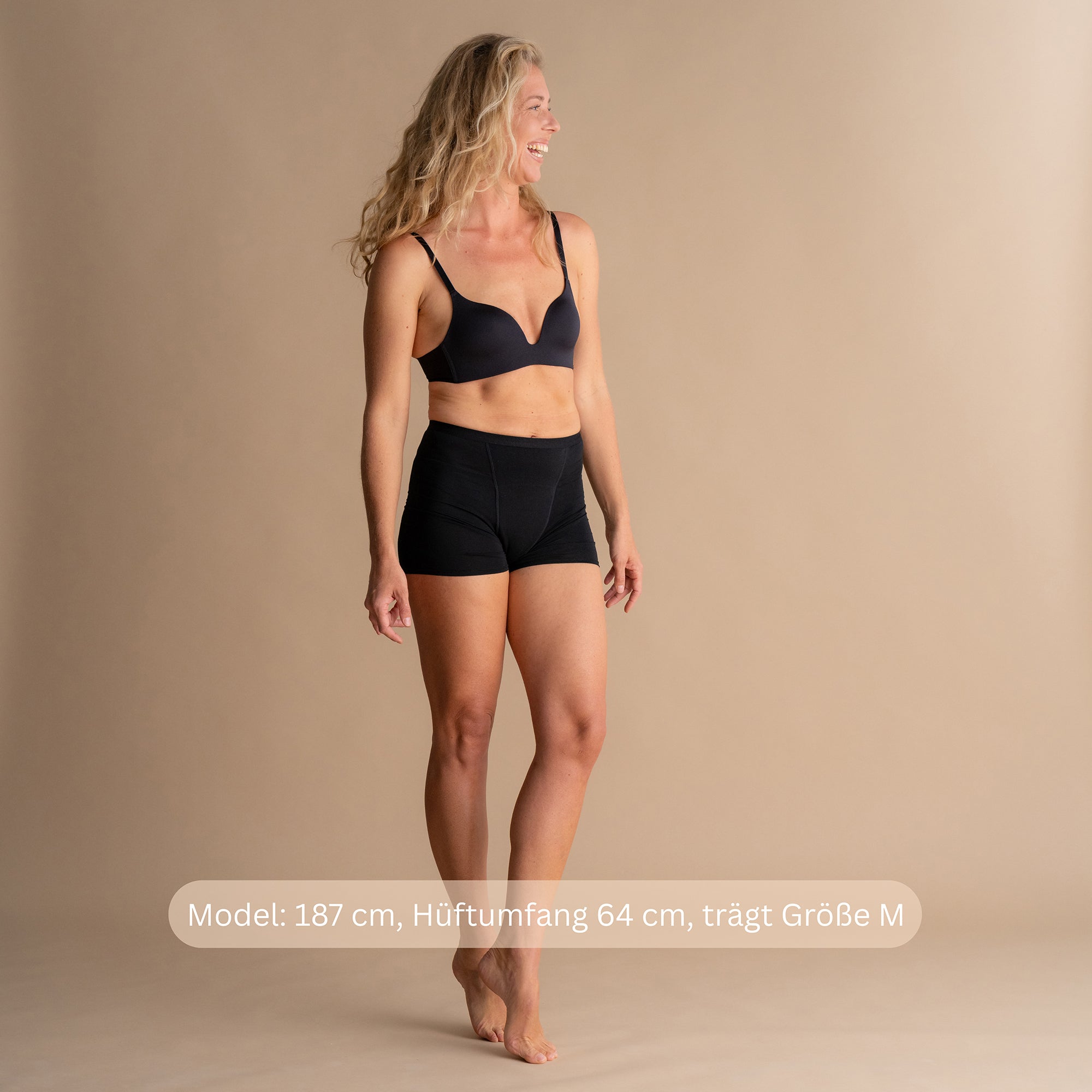 Model 187 cm groß, Hüftumfang 64 cm, trägt Größe M der schwarzen Floena Leakproof Bamboo Sleep Short Perioden-Schlafshorts, mit Größenhinweis
