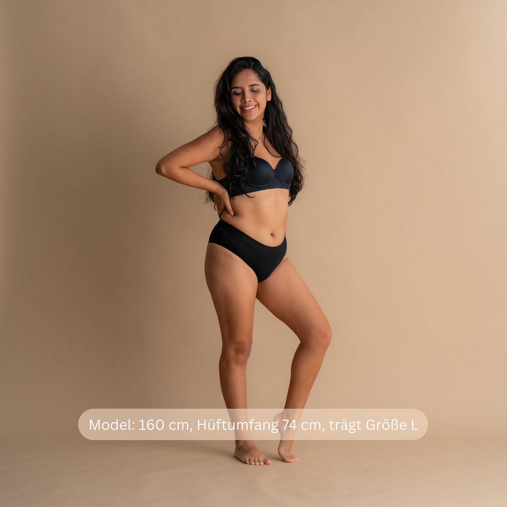 Model 160 cm groß, Hüftumfang 74 cm, trägt Größe L der schwarzen Floena Leakproof Everyday Bamboo Bikini, Periodenunterwäsche aus Bambus, Frontansicht mit Größenhinweis