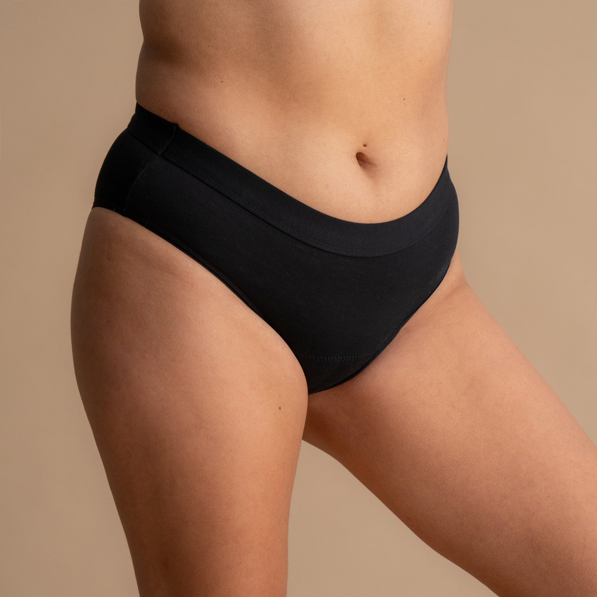 Vollständige Seitenansicht eines Models in der schwarzen Floena Leakproof Everyday Bamboo Bikini, Periodenunterwäsche aus Bambus, mit glattem Bund