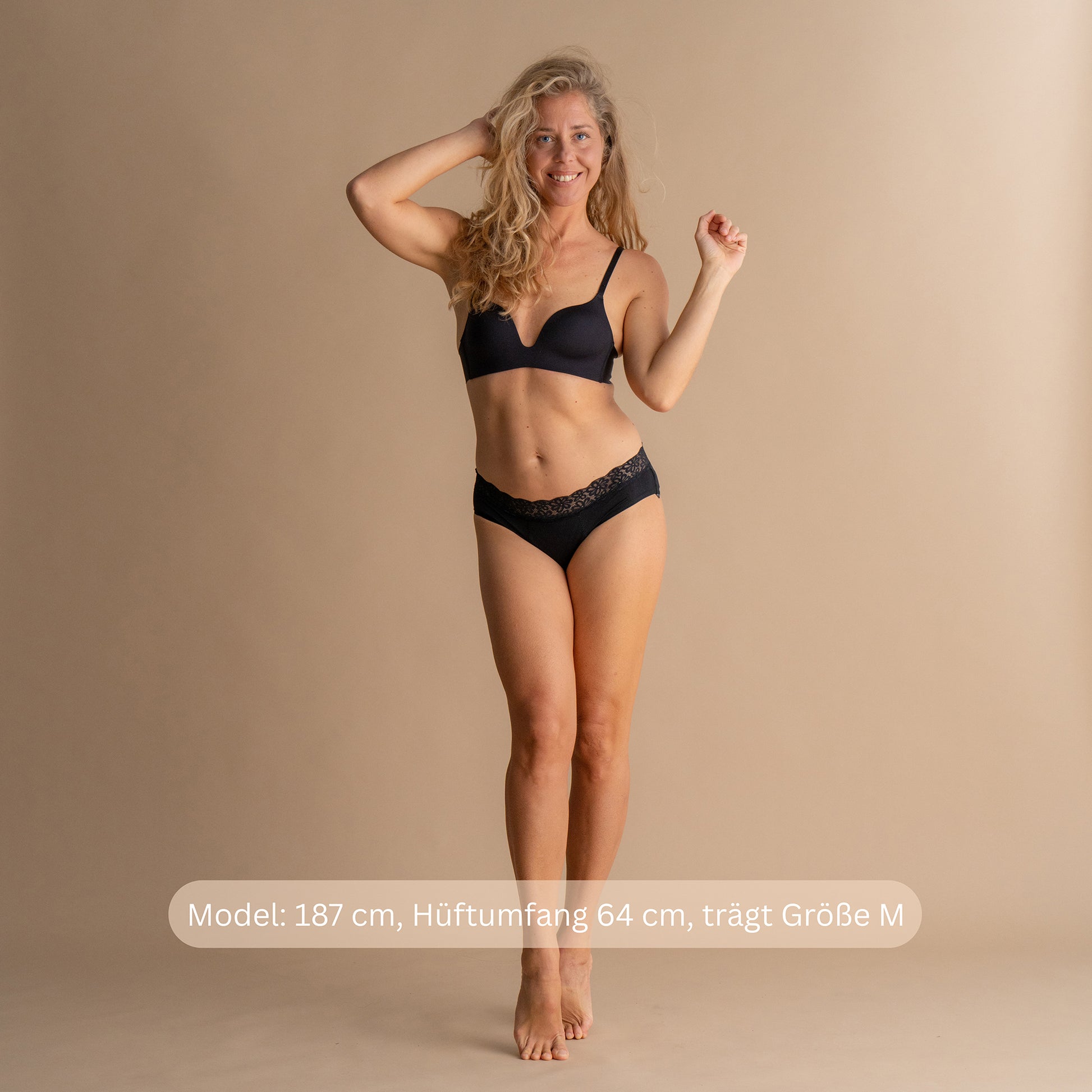 Model 187 cm groß, Hüftumfang 64 cm, trägt Größe M der schwarzen Floena Leakproof Soft Cotton Brief, Periodenunterwäsche aus Baumwolle, Ganzkörper-Frontansicht mit Größenhinweis