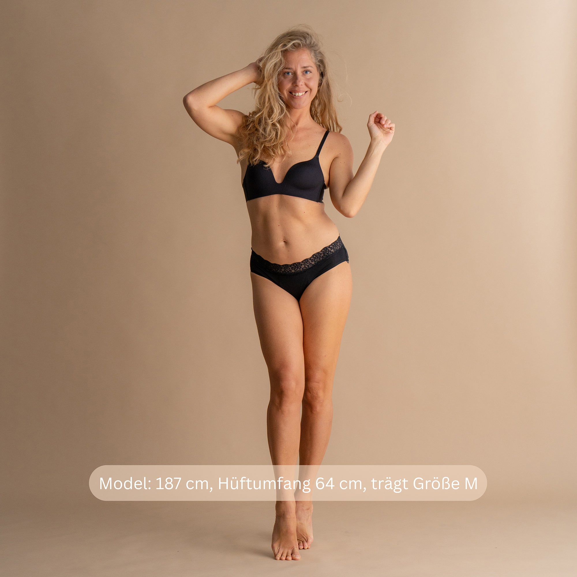 Model 187 cm groß, Hüftumfang 64 cm, trägt Größe M der schwarzen Floena Leakproof Soft Cotton Brief, Periodenunterwäsche aus Baumwolle, Ganzkörper-Frontansicht mit Größenhinweis