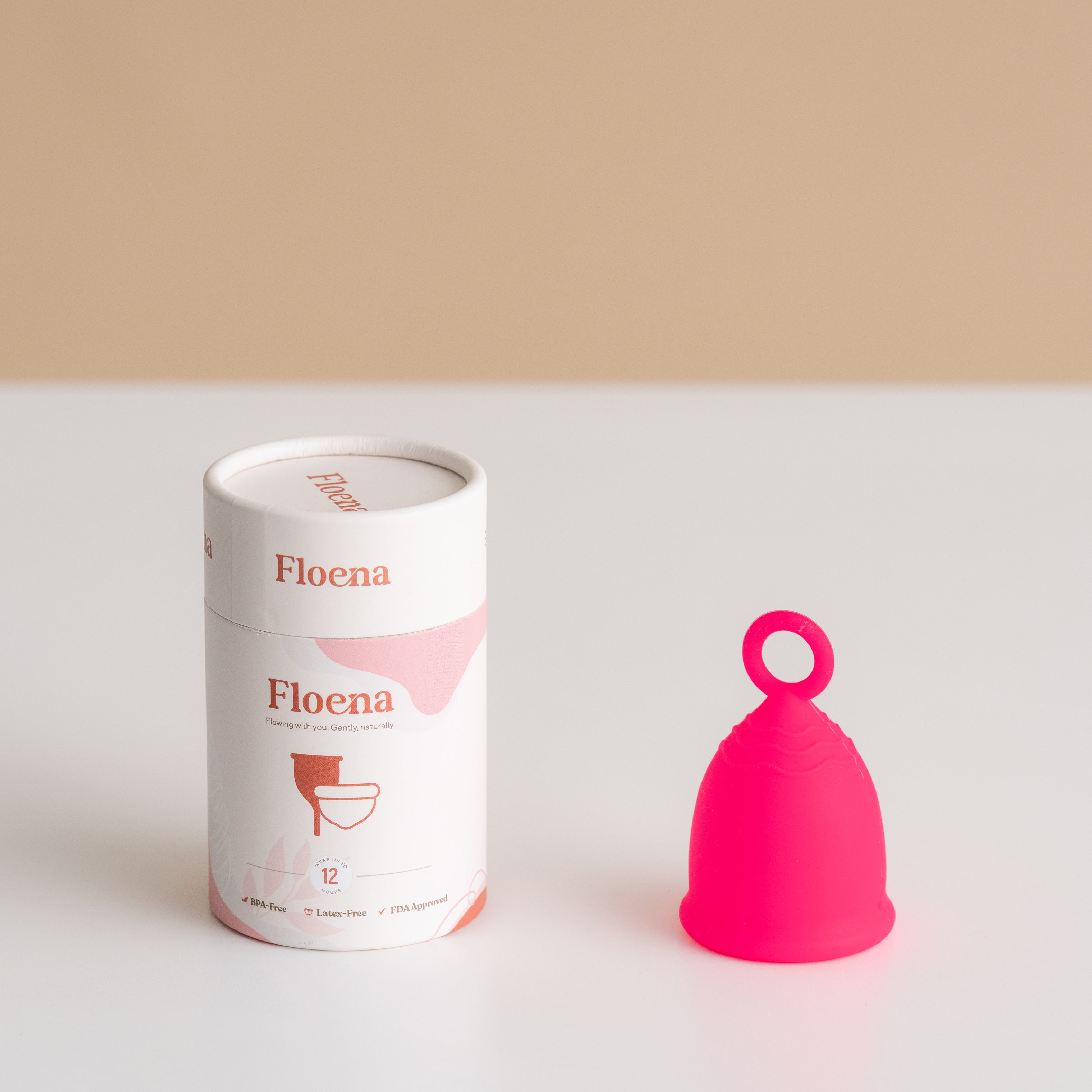 Floena Ring Cup — rosa Menstruationstasse mit ergonomischem Ringgriff neben ihrer Verpackung, bis zu 12 Stunden auslaufsicherer Schutz