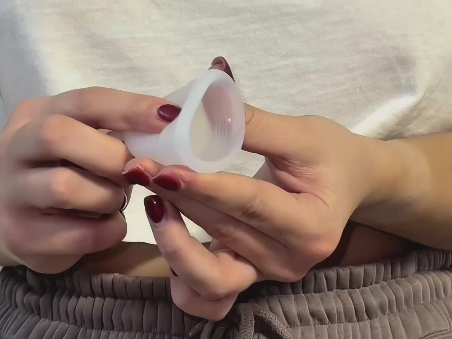 Video laden: Hände zeigen die U-Falttechnik zum Einführen einer Menstruationstasse oder eines Menstruationsdisks, mit Schritt-für-Schritt-Faltmethode.